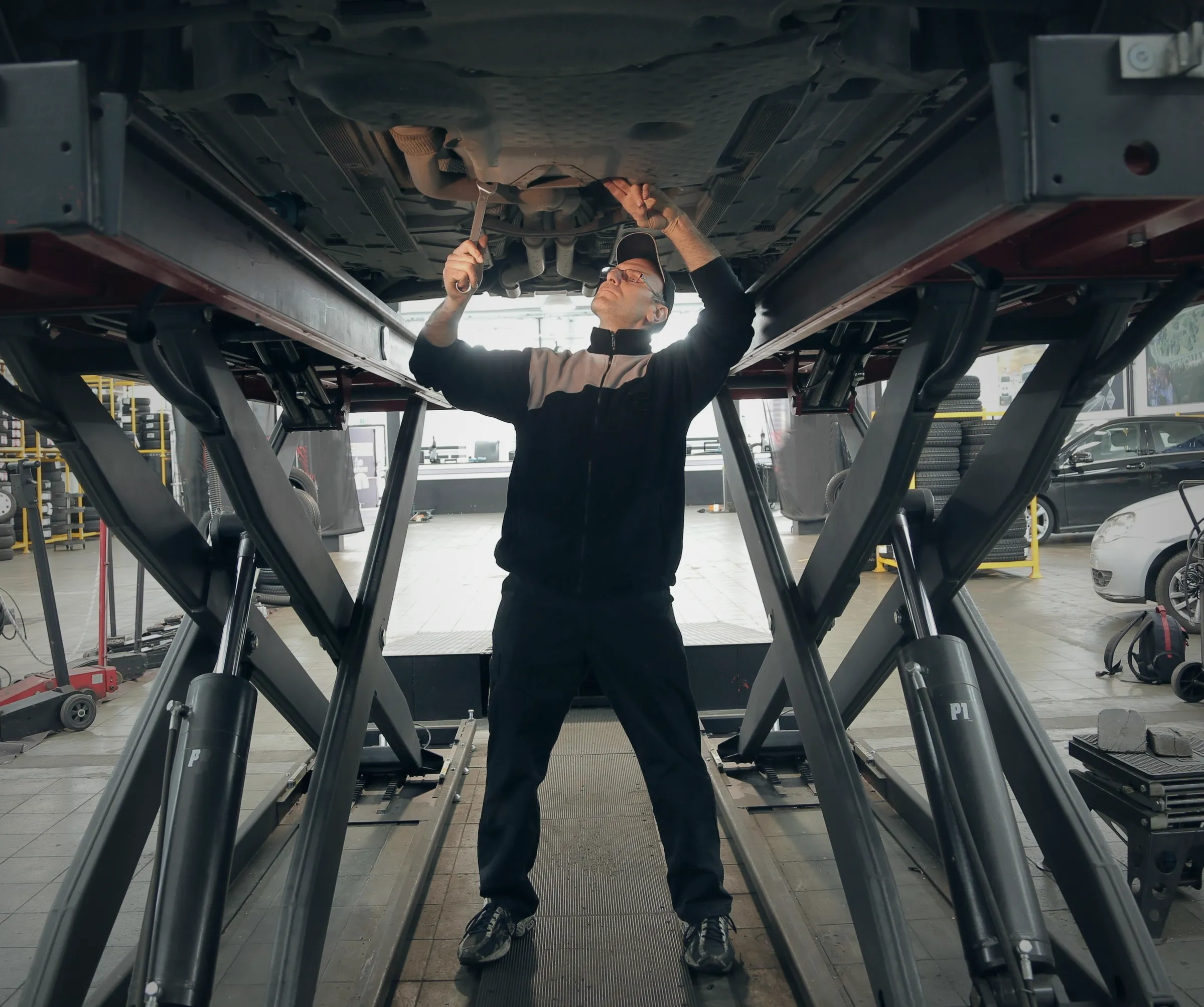 Technician inspecting the underside of a car raised on a lift