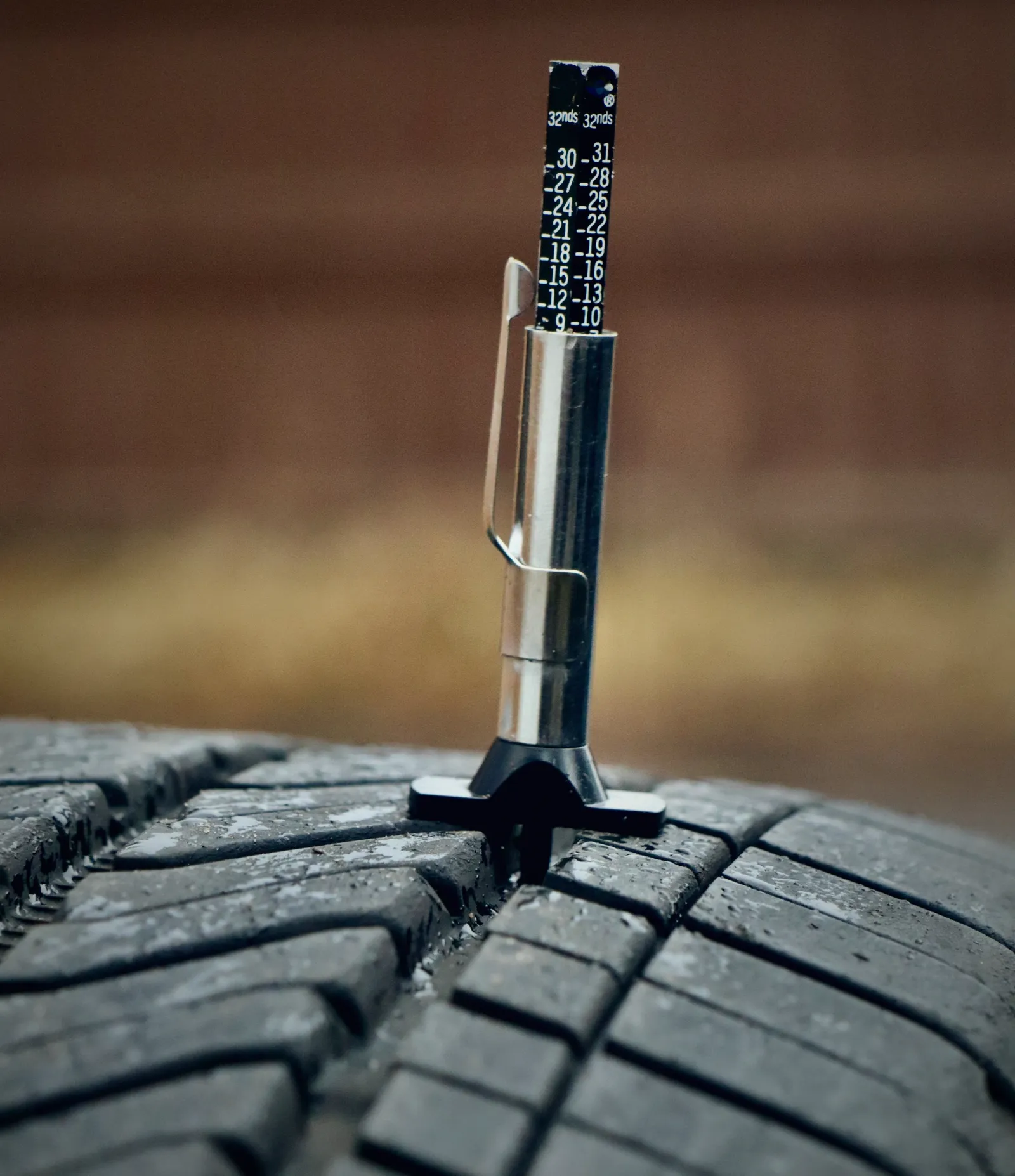 Tread-depth gauge standing in a tire tread, measuring how much is left