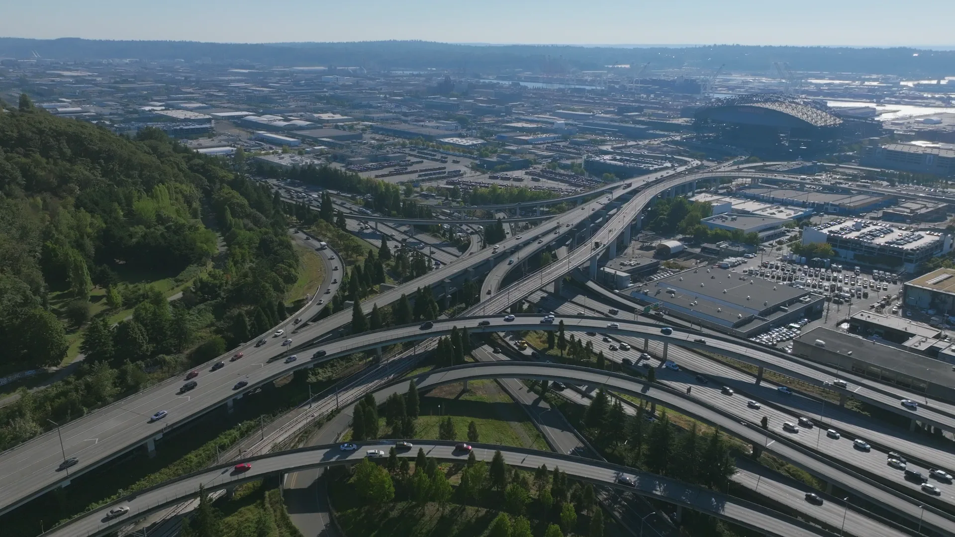 Aerial view of a busy multi-level highway interchange in the evening, cars moving across the ramps.