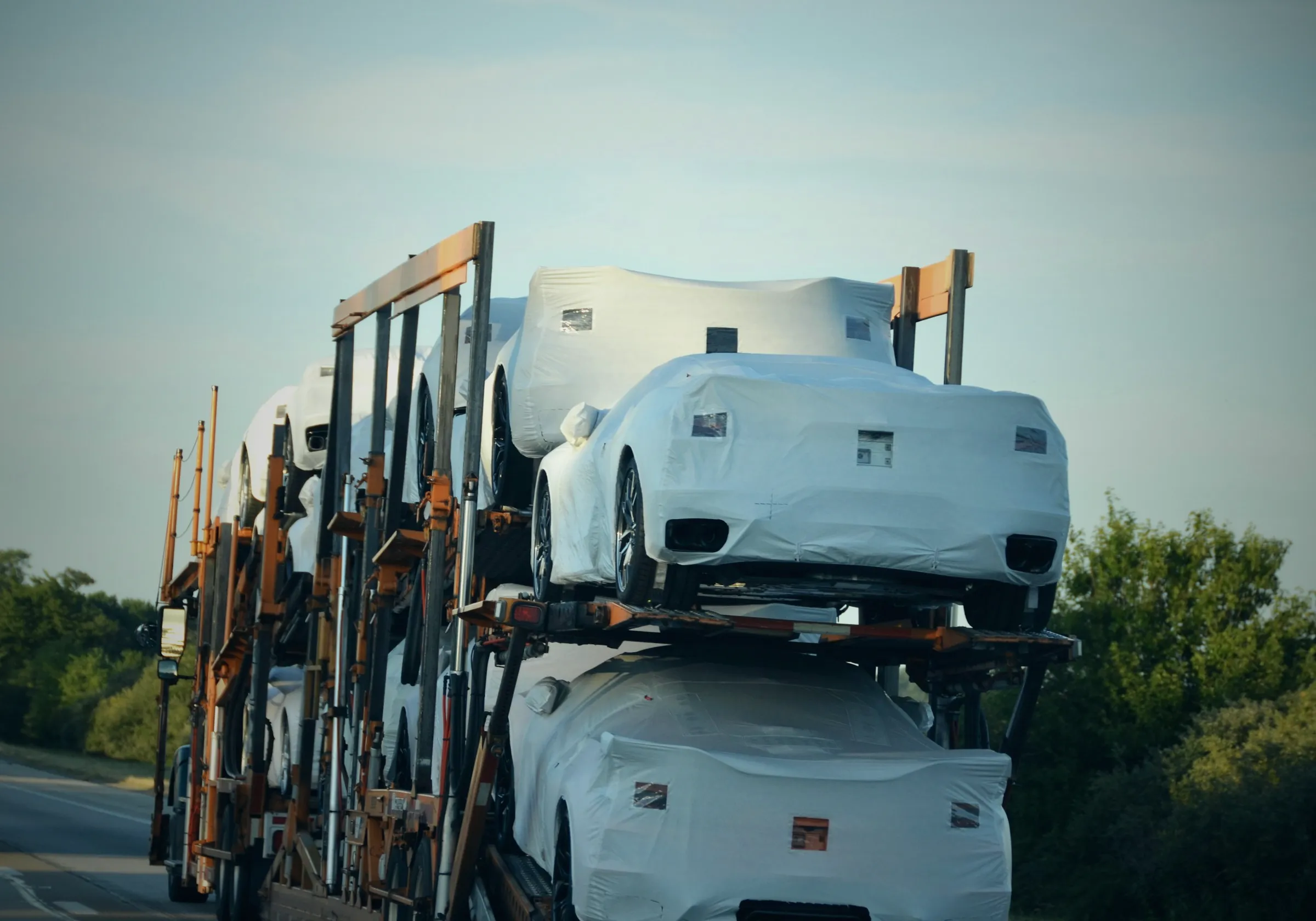 New cars under protective covers on a car carrier